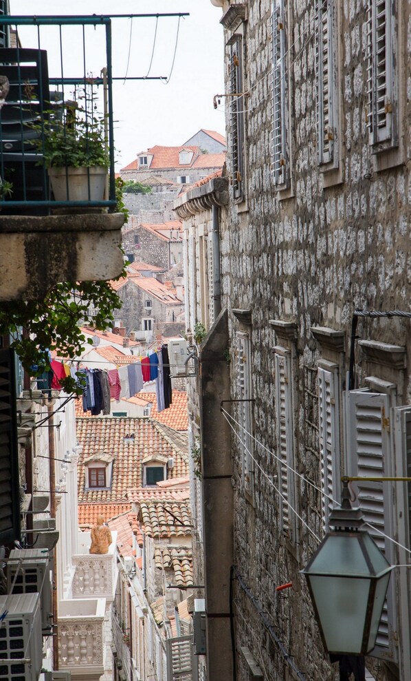 Una calle estrecha con edificios de arquitectura tradicional, incluyendo fachadas de piedra y tejados de tejas. Ropa colgada en un tendedero, indicando una zona residencial.