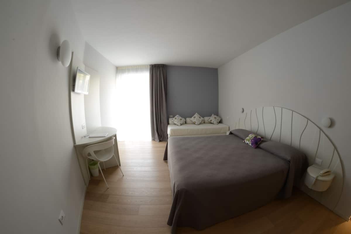 A bedroom with a bed, a desk, and a chair.