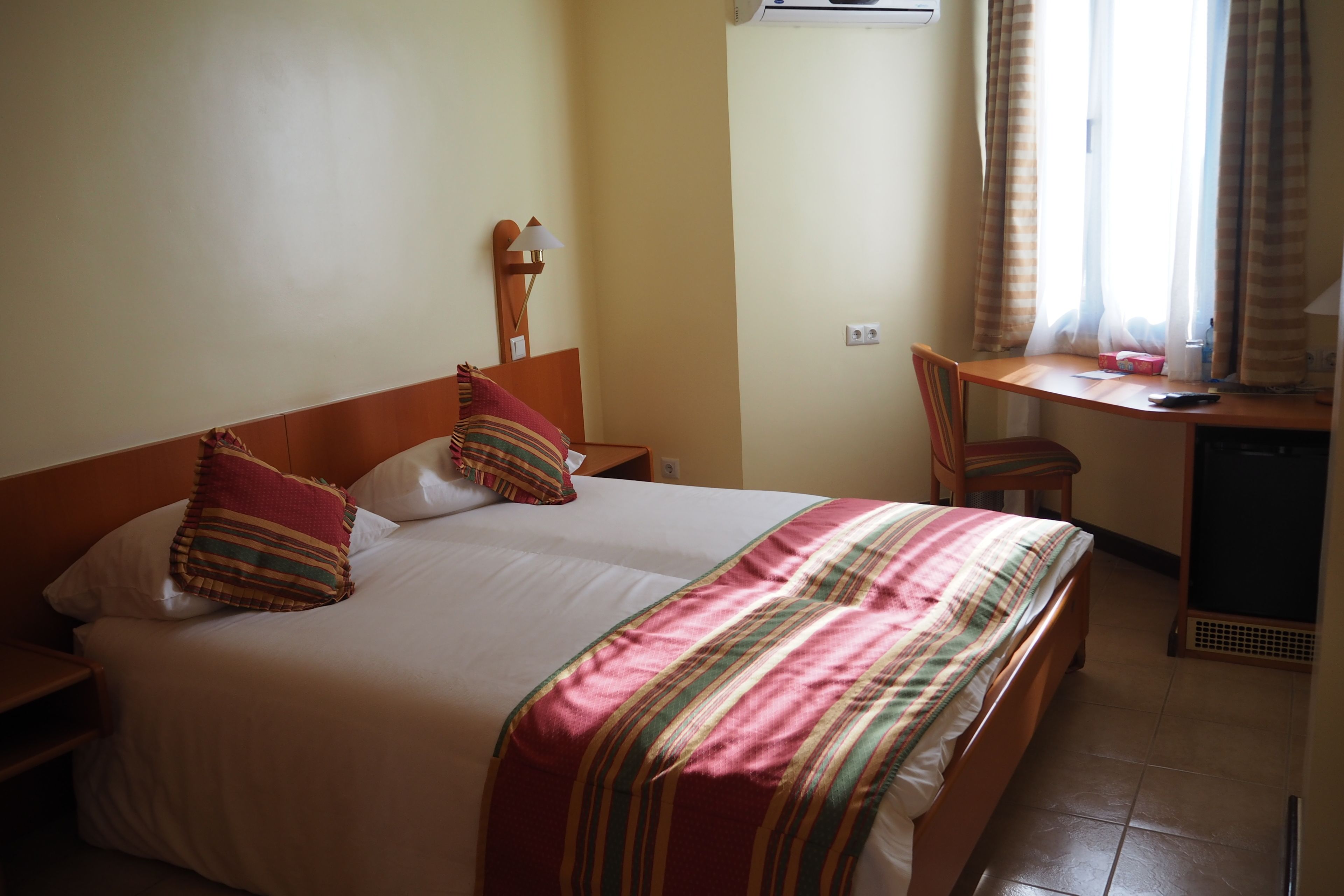 A hotel room with a bed, a desk, and a chair.