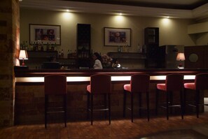 Un espace bar avec un comptoir, des tabourets de bar et un barman.
