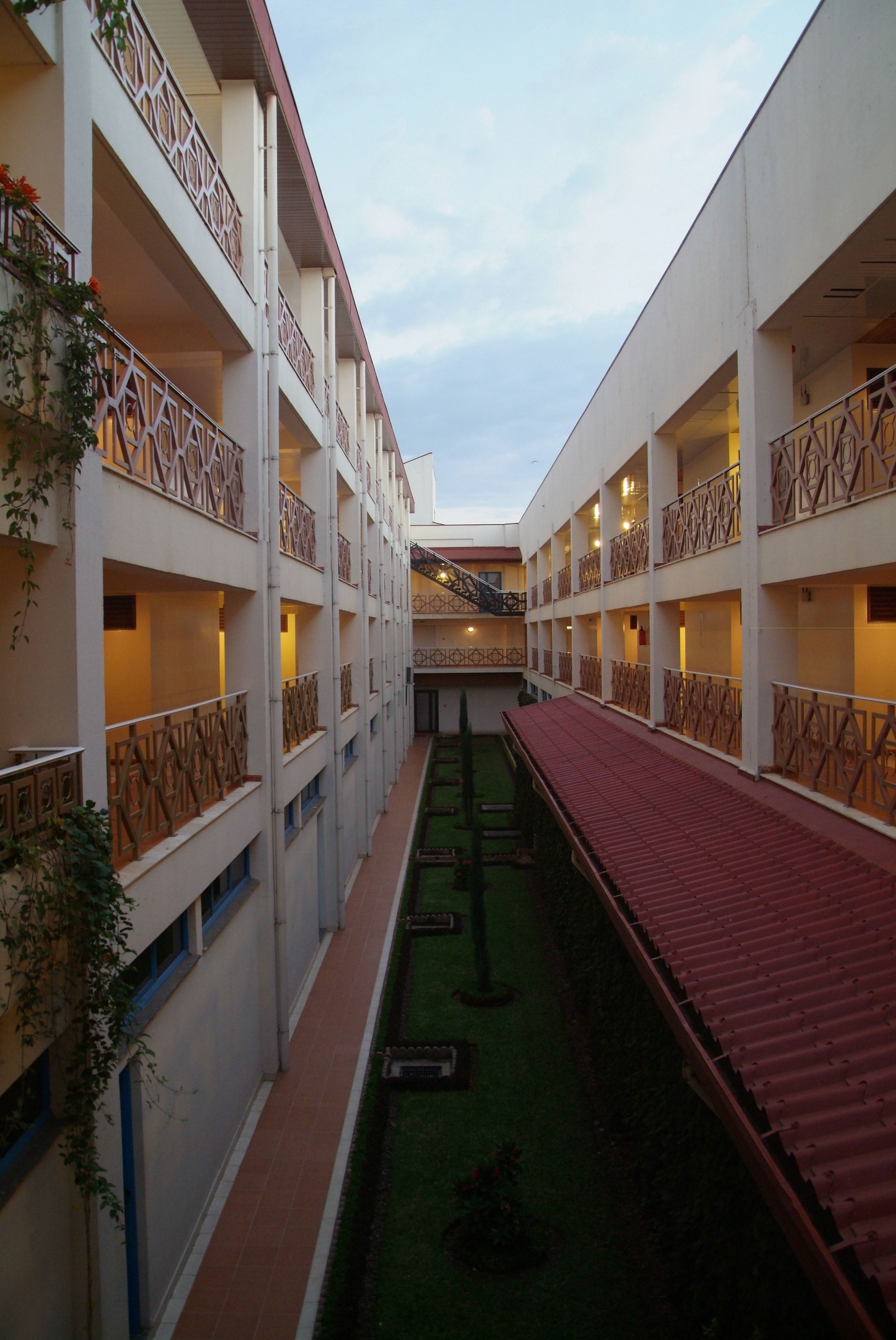 A multi-story hotel with balconies, a central courtyard, and a red-roofed walkway.