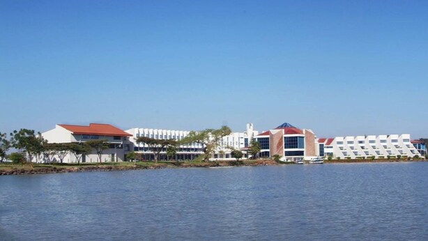 Um hotel à beira-mar com vários edifícios, incluindo um com telhado vermelho característico e uma estrutura moderna com um design geométrico original.