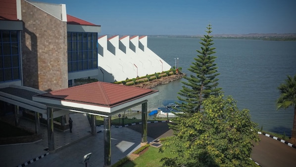 A modern building with a glass facade, a red roof, and a view of a calm lake.