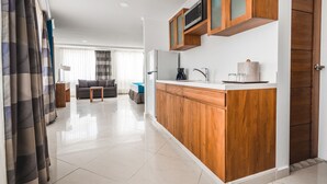 A modern kitchen with wooden cabinets, a microwave, and a coffee maker. - Majestic City Suites & Beach Hotel (Willemstad)