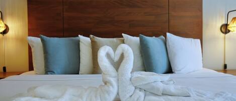 Une chambre d’hôtel avec une tête de lit en bois, du linge de lit blanc et des coussins décoratifs.