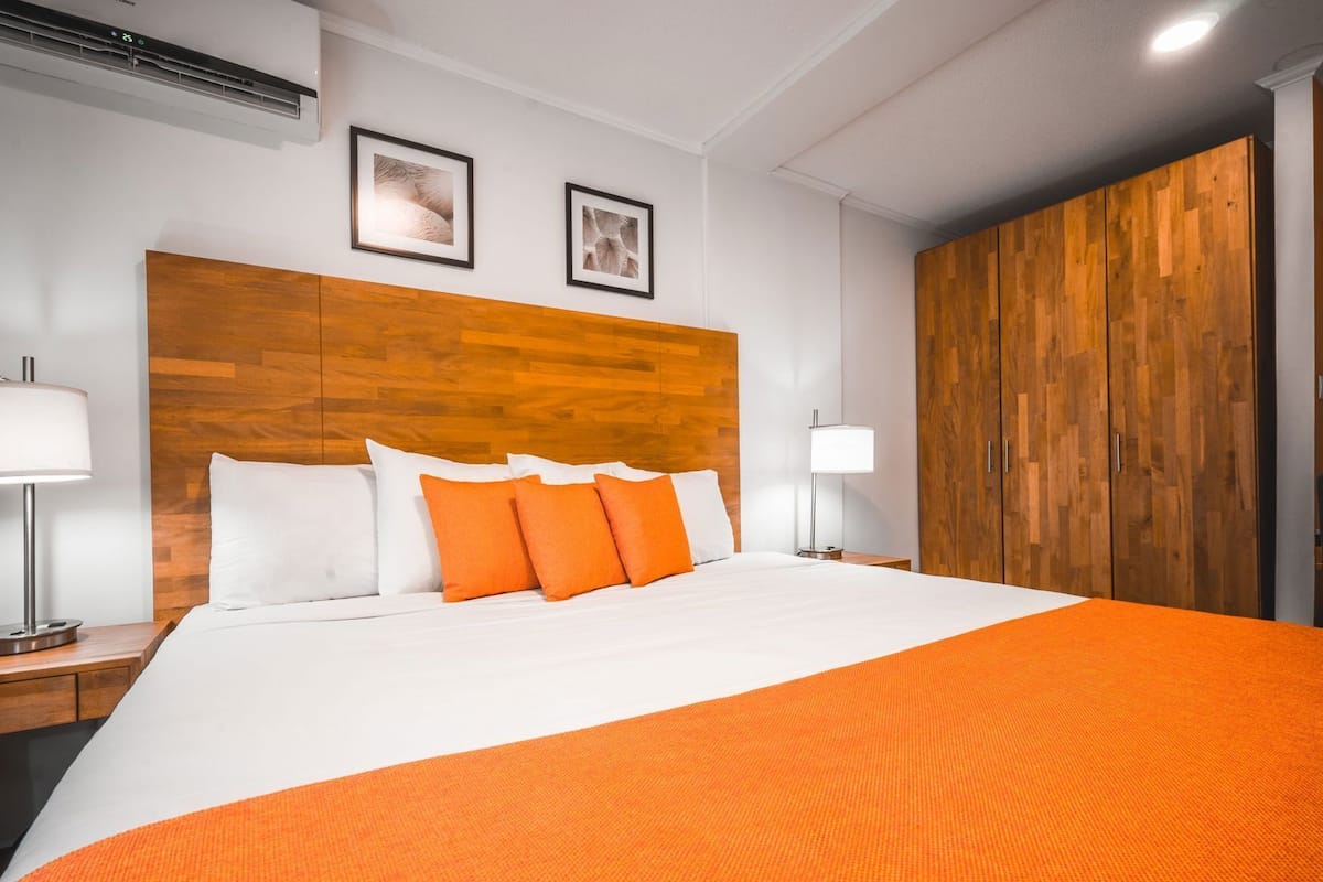 Habitación de hotel con una cama grande, cabecera de madera, dos cuadros enmarcados en la pared y un armario.