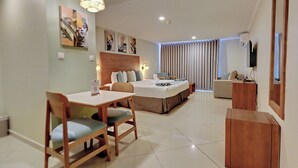 A modern hotel room with a bed, a desk, and a dining area. - Majestic City Suites & Beach Hotel (Willemstad)