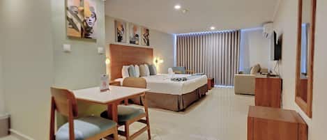 Quarto de hotel moderno com uma cama, uma escrivaninha e um espaço para refeições.