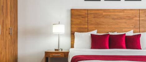 A hotel room with a wooden headboard, a bedside table with a lamp, and three framed pictures on the wall.