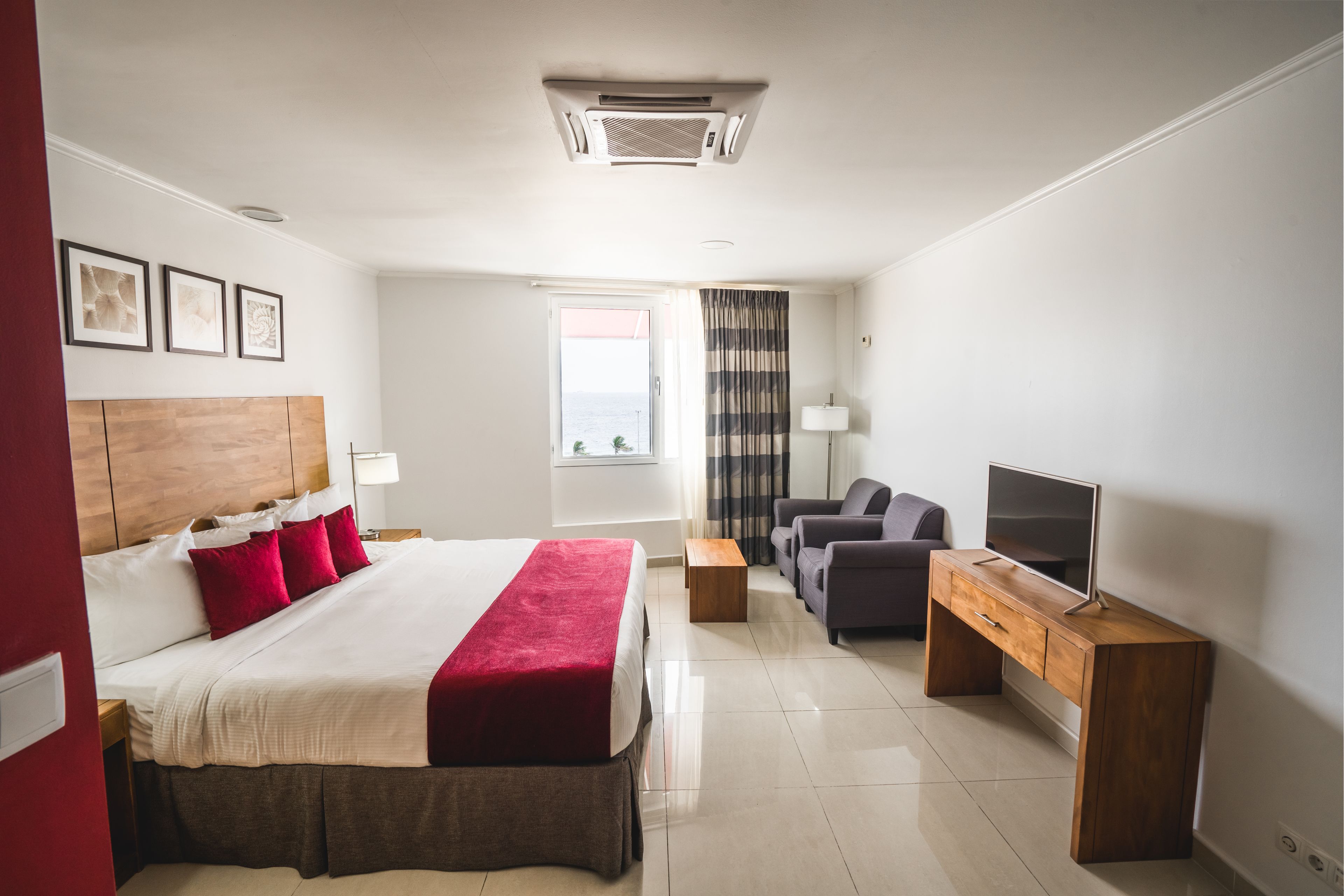Ein Hotelzimmer mit Bett, Fernseher, Schreibtisch und einer Sitzecke.
