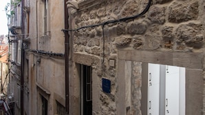 A narrow stone building with a small entrance, a visible door, and a staircase leading to the entrance. - Apartments Bottega (Dubrovnik)