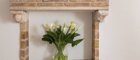 A framed picture with a vase of white flowers on a brick wall.