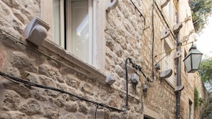 A stone building with a narrow staircase, a fire extinguisher, and a blue sign. - Apartments Bottega (Dubrovnik)
