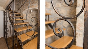 A staircase with wooden steps and wrought iron railings against a stone wall. - Apartments Bottega (Dubrovnik)