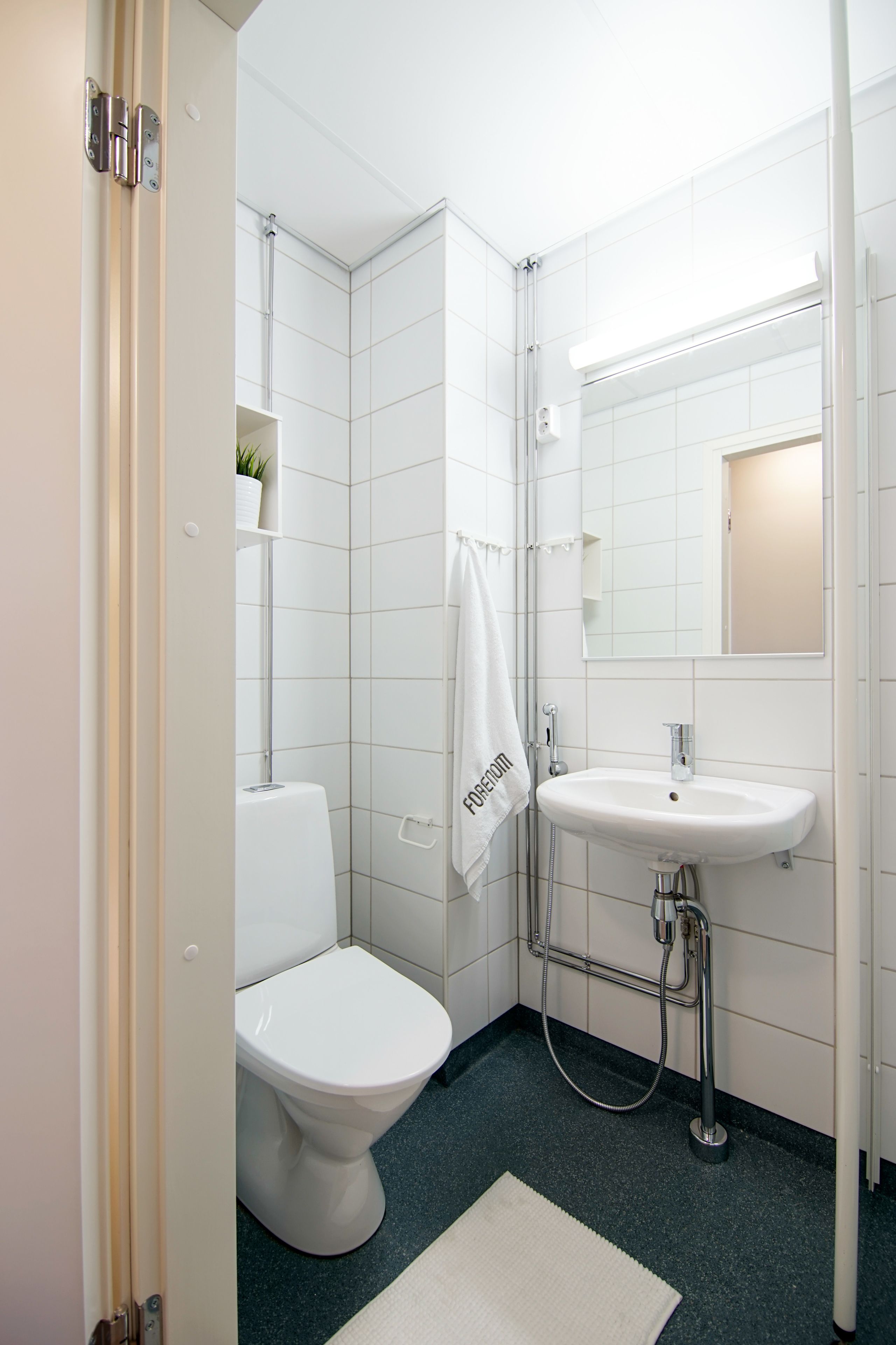 A modern bathroom with a white toilet, a sink, and a mirror.