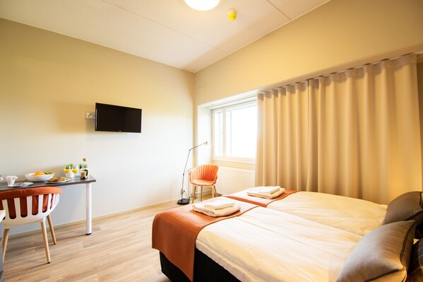 A hotel room with a bed, a desk with a chair, a television, and a window with curtains. - Forenom Aparthotel Espoo Leppävaara (Espoo)