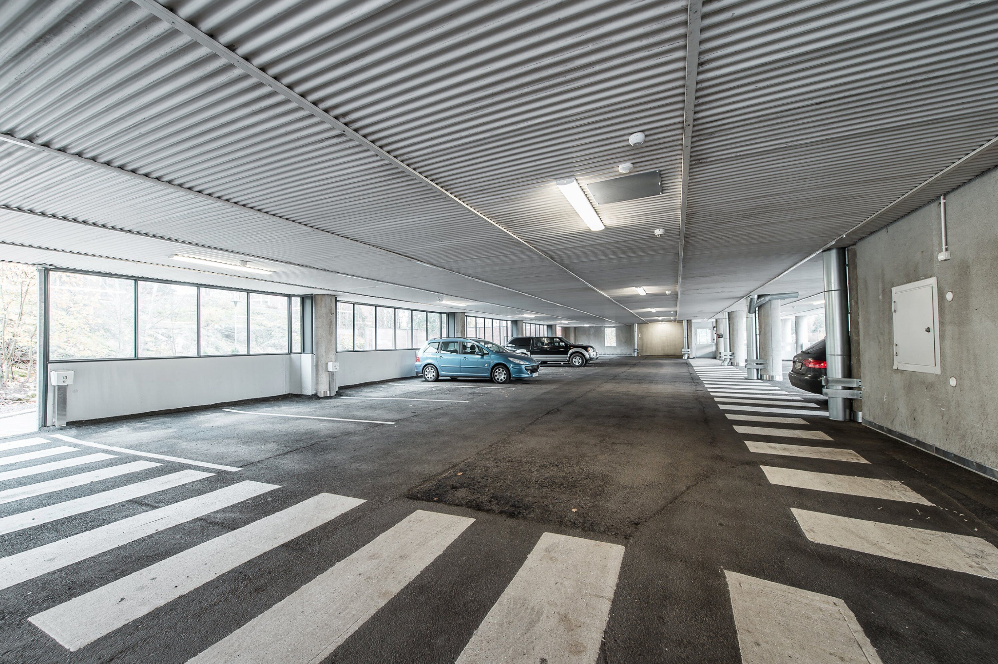 Een parkeergarage met meerdere verdiepingen, aangeduide voetgangersoversteekplaatsen en auto's geparkeerd op verschillende niveaus.
