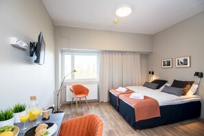 A modern hotel room with a bed, two bedside tables, a chair, a dining area with a table and chairs, and a window with curtains. - Forenom Aparthotel Espoo Leppävaara (Espoo)