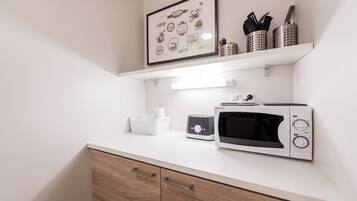 A kitchen with a microwave, toaster, and a framed coffee-themed artwork above the counter.