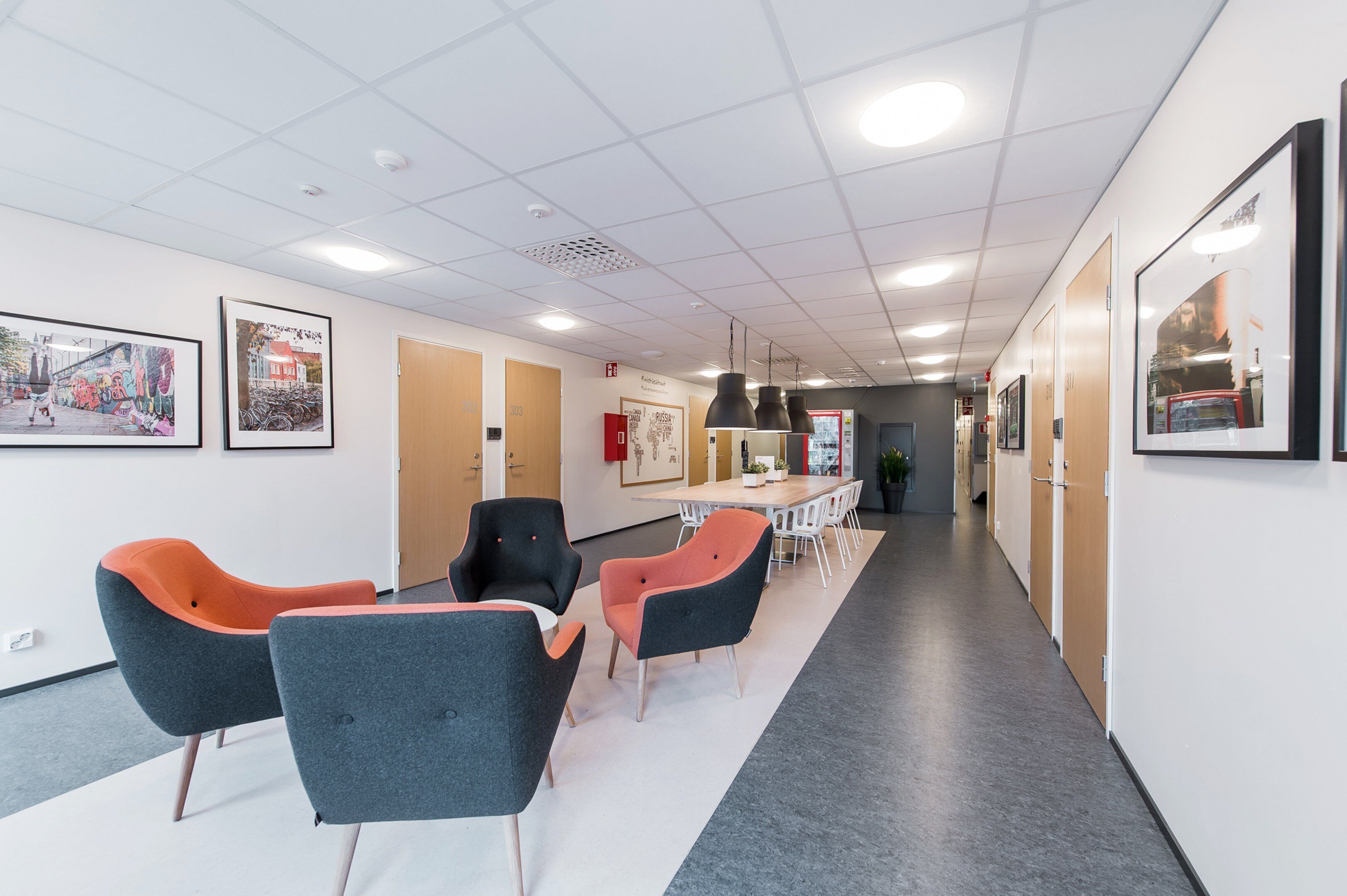 A modern office space with a long table, several chairs, and framed pictures on the walls.