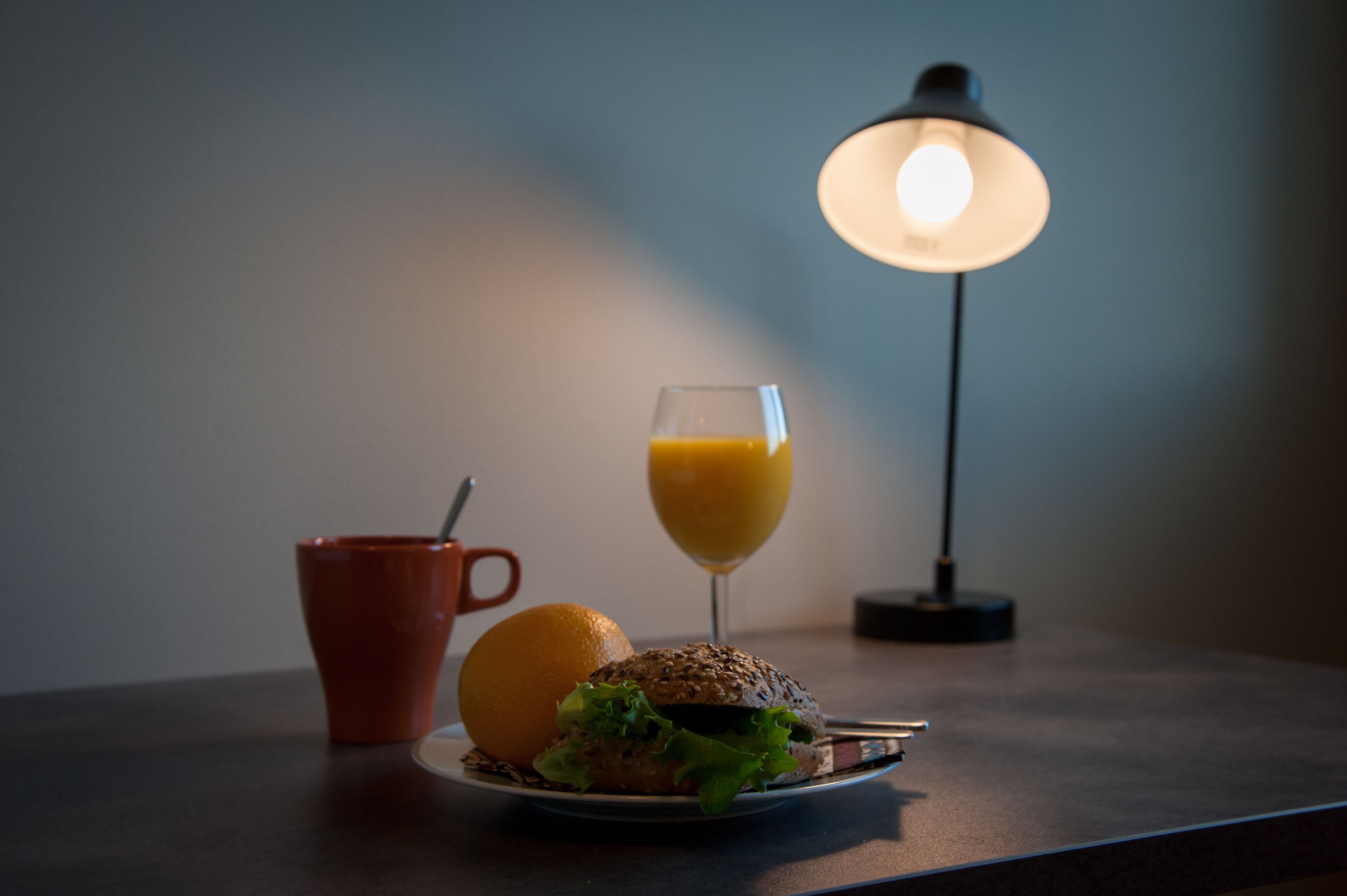Una mesa con un plato de comida, un vaso de zumo de naranja y una taza.