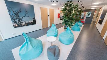 A hallway with teal bean bag chairs, a white table, and a large tree.