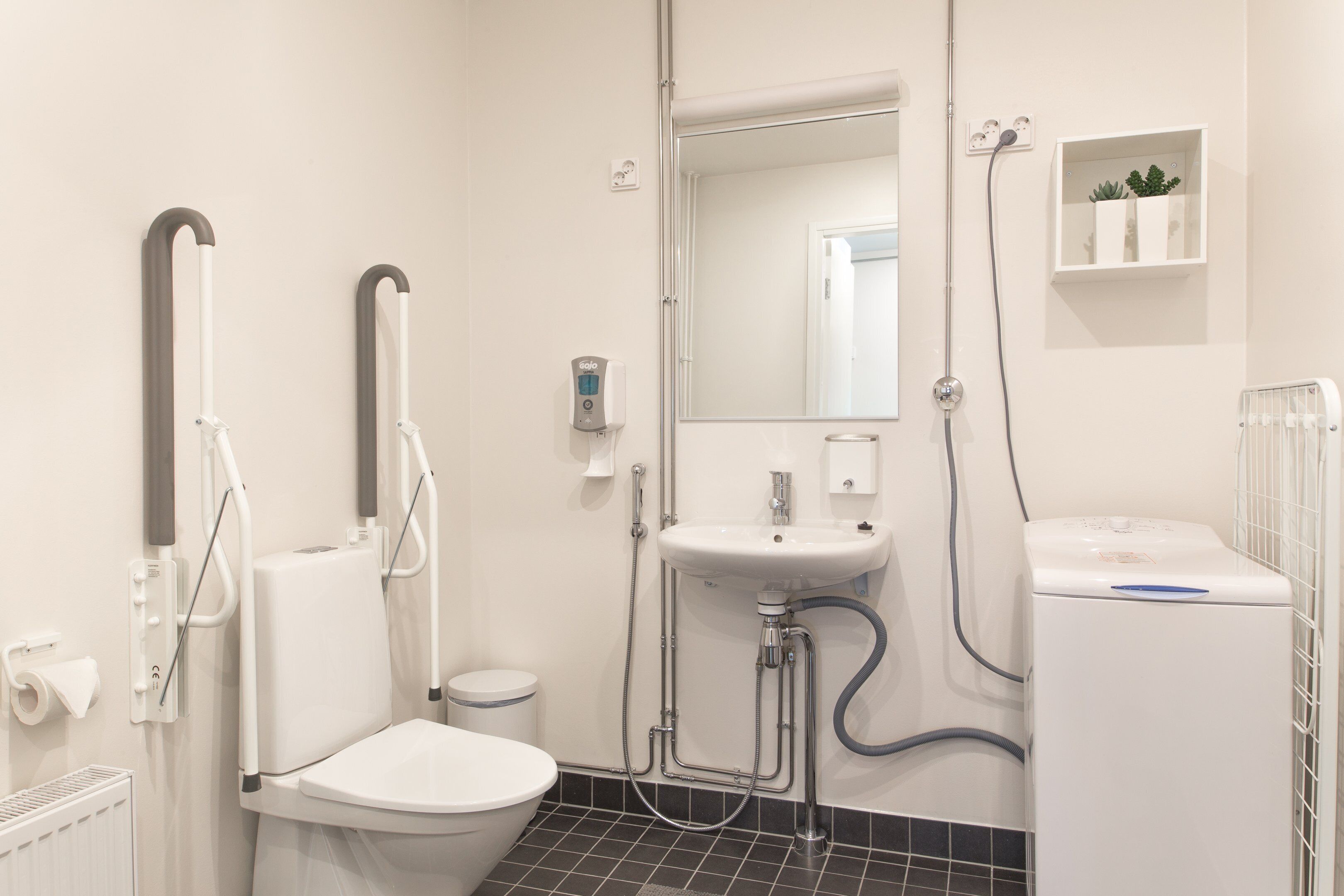 A modern bathroom with a toilet, bidet, sink, and mirror.