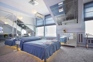 Una habitación de hotel moderna con una cama grande, un escritorio y un ventanal amplio.