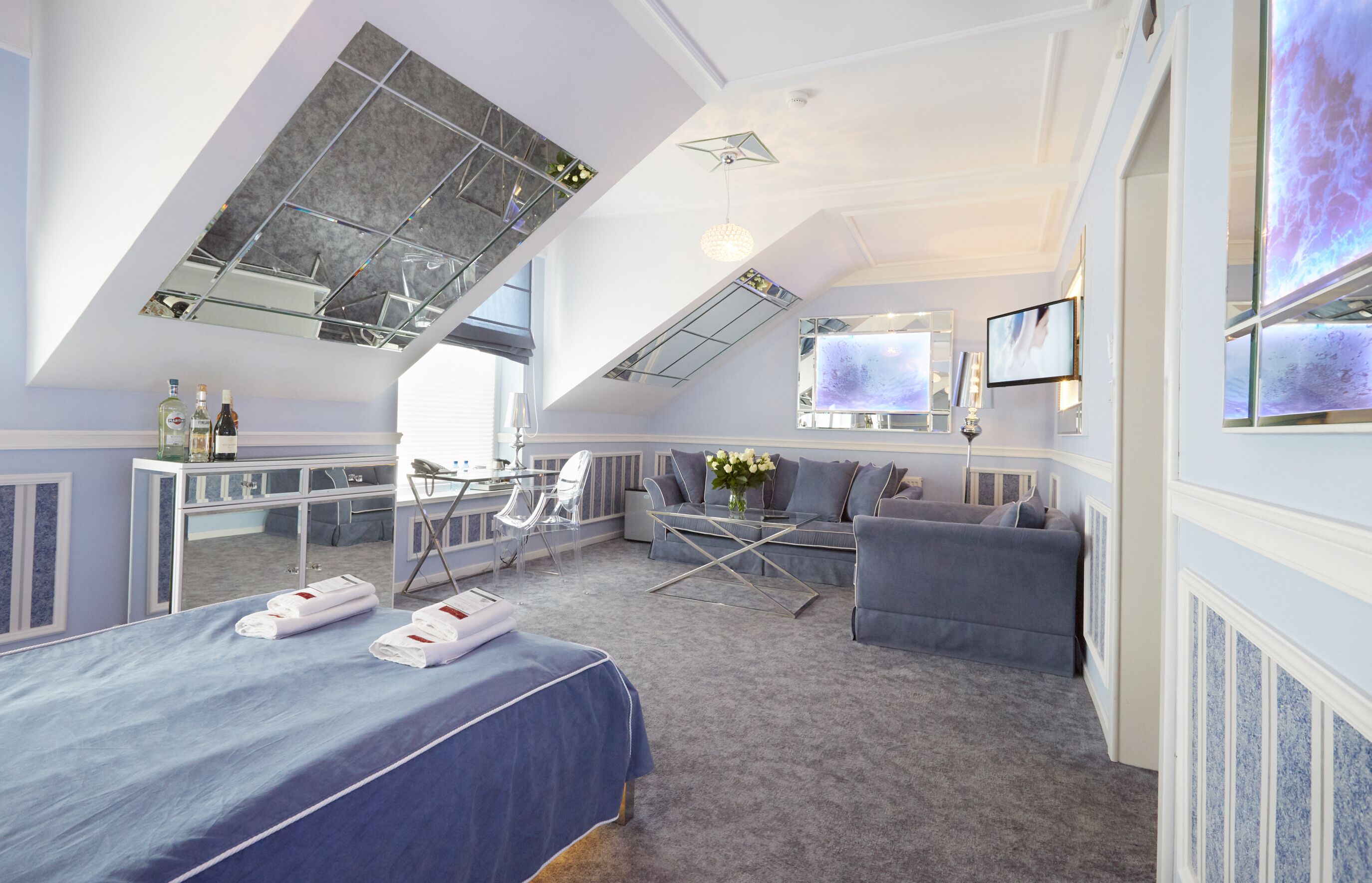 Habitación de hotel con una cama grande, un sofá, un escritorio con una silla, un televisor y un balcón con vistas.