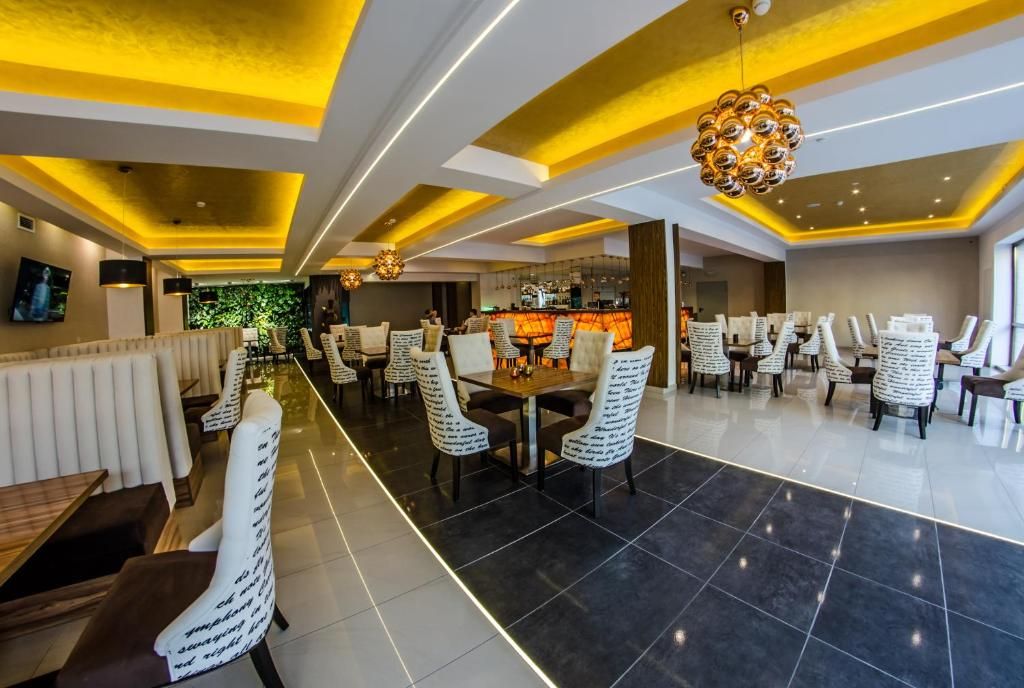 Um hall de hotel moderno com área de bar, sofás e uma luminária decorativa no teto.