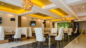Een modern restaurant met hoge plafonds, inbouwverlichting en bijzondere stoelen met sierlijke ontwerpen.