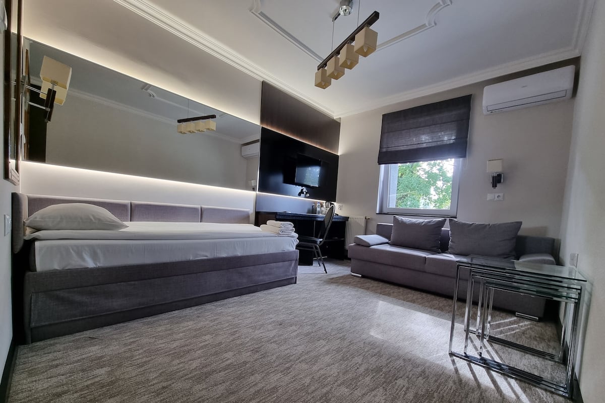Une chambre moderne avec un grand lit, un canapé, un bureau et un téléviseur.