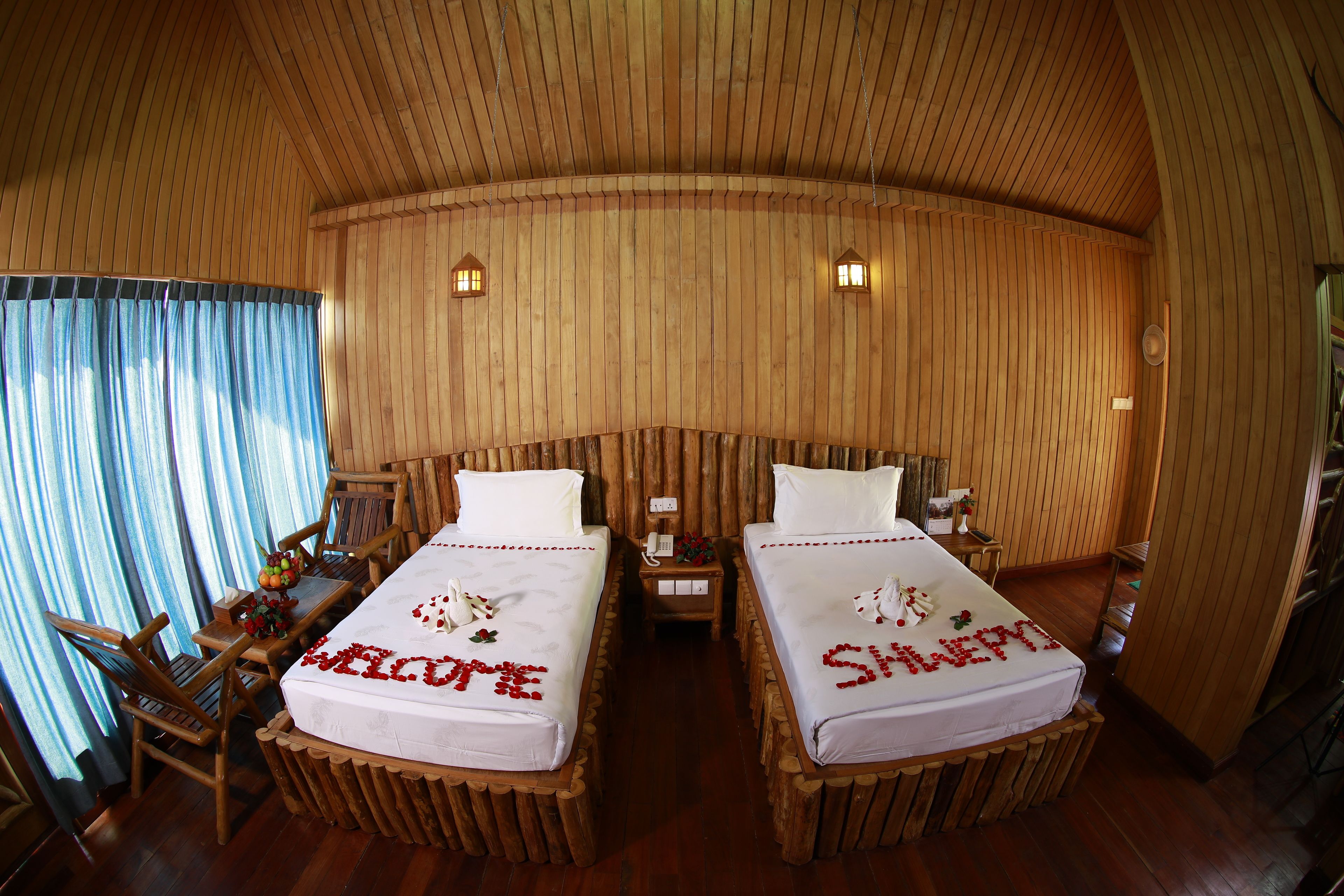 A room with two beds, wooden walls, and a curved ceiling.