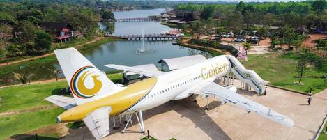 A Golden Airways airplane parked at an airport with a lake and greenery in the background.