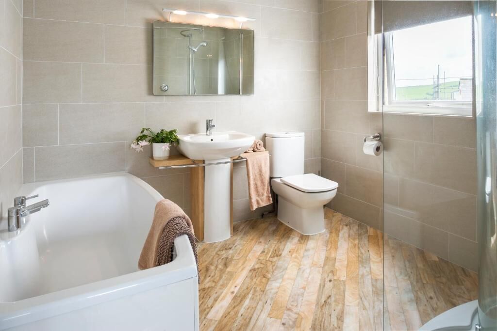 Een moderne badkamer met bad, wastafel, toilet en een douchecabine van glas.
