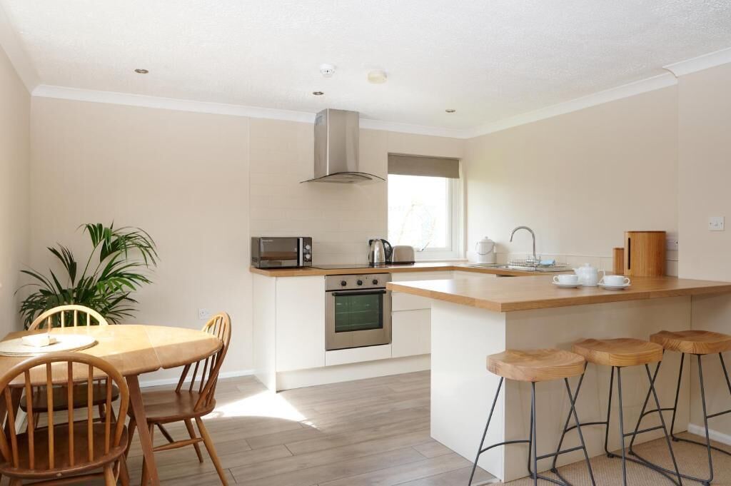 A modern kitchen with a central island, built-in oven, microwave, and stainless steel sink.