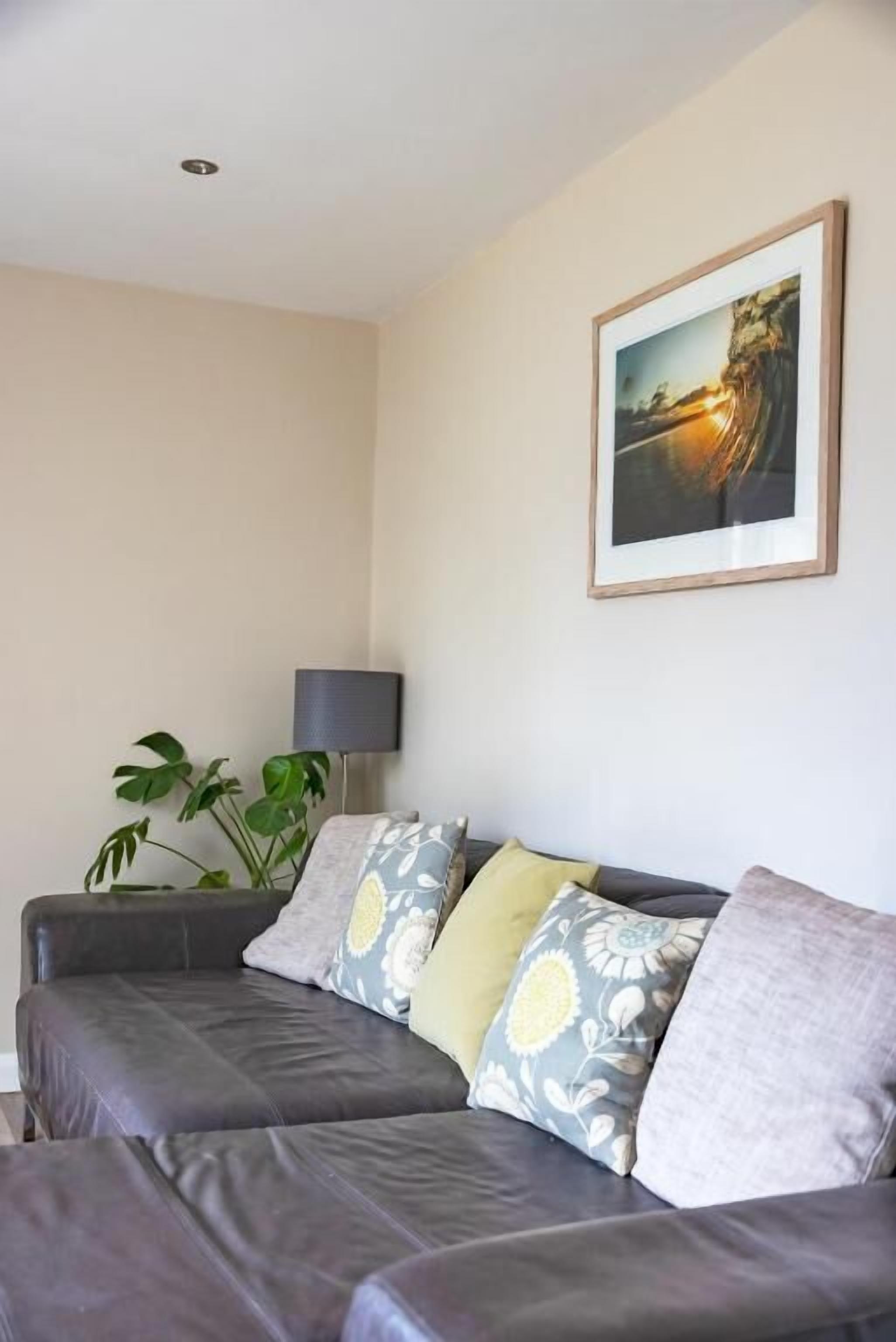 Un salon avec un canapé, une lampe et un tableau encadré au mur.