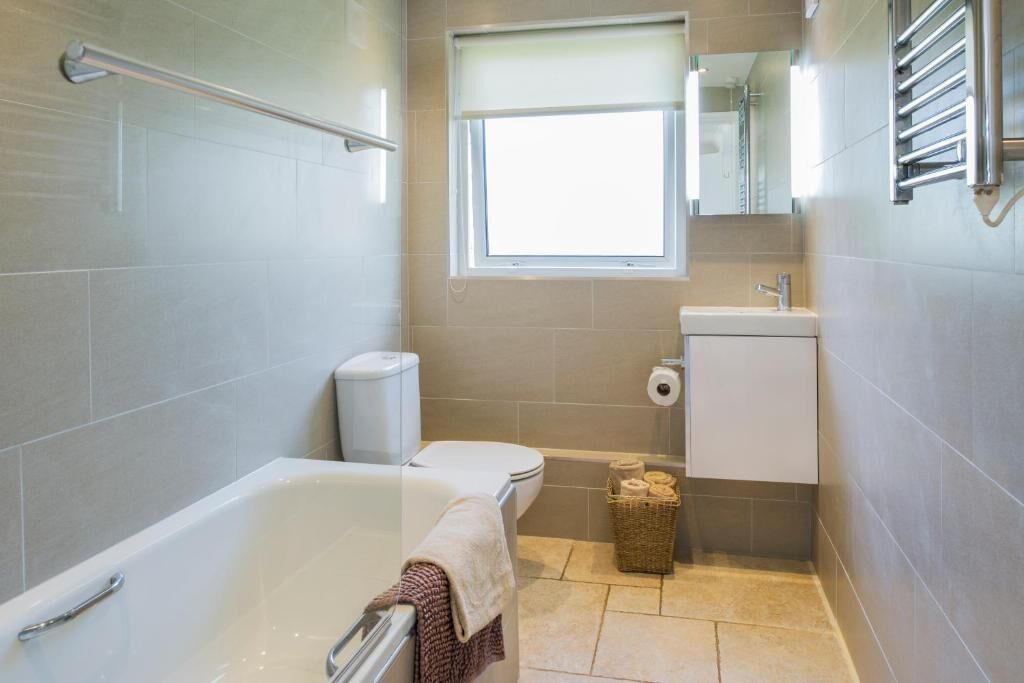 Un baño con bañera, inodoro, lavabo y ventana.