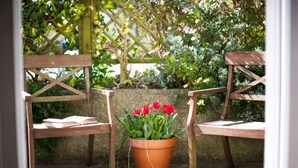 Two wooden chairs with a potted red tulip plant between them. - Gwithian Holidays, Godrevy House (Hayle)