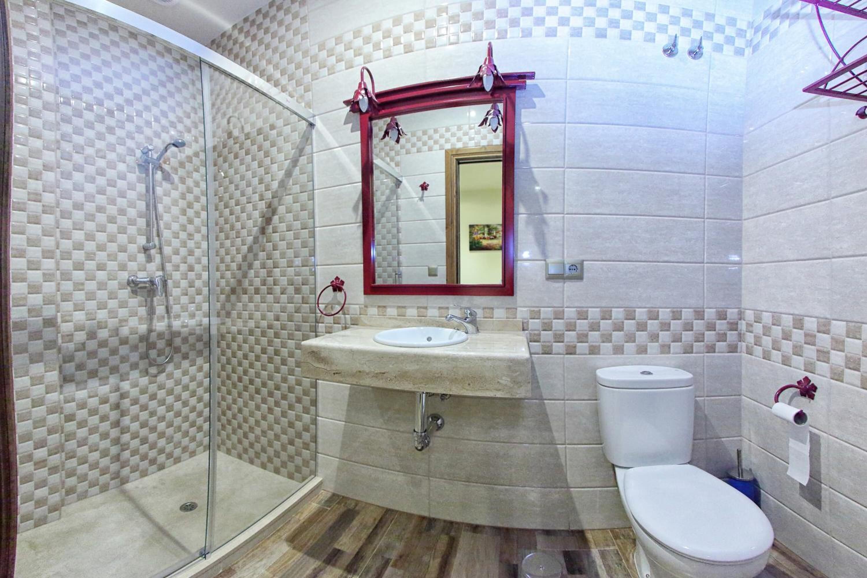 A bathroom with a glass shower enclosure, a sink with a mirror above it, and a toilet.