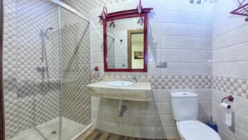 A bathroom with a glass shower enclosure, a sink with a mirror above it, and a toilet.