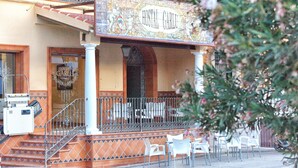 A hotel with a tiled facade, a balcony with metal railings, and outdoor seating. - Hostal Garlu (La Rambla)