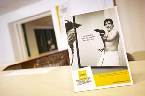 Un folleto con un hombre sosteniendo un secador de pelo, texto en francés y una dirección web.