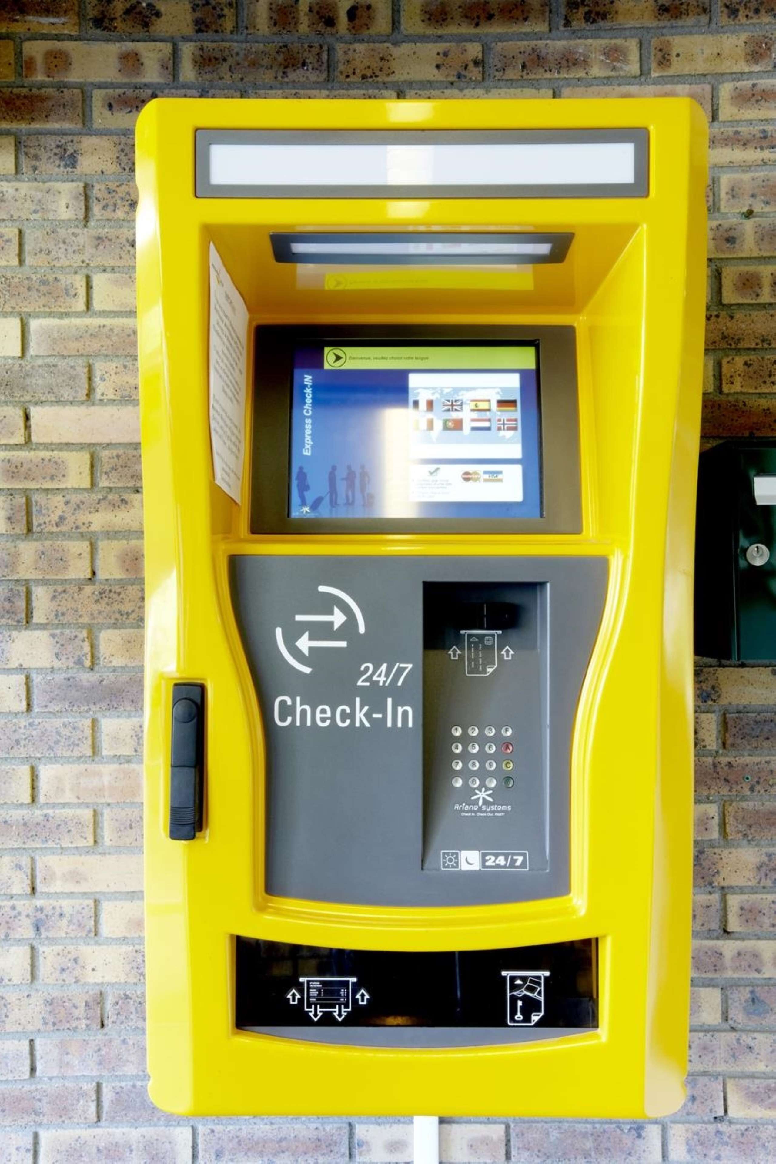 Un terminal d’enregistrement jaune, accessible 24 heures sur 24 et 7 jours sur 7, doté d’une interface à écran tactile et d’un clavier.