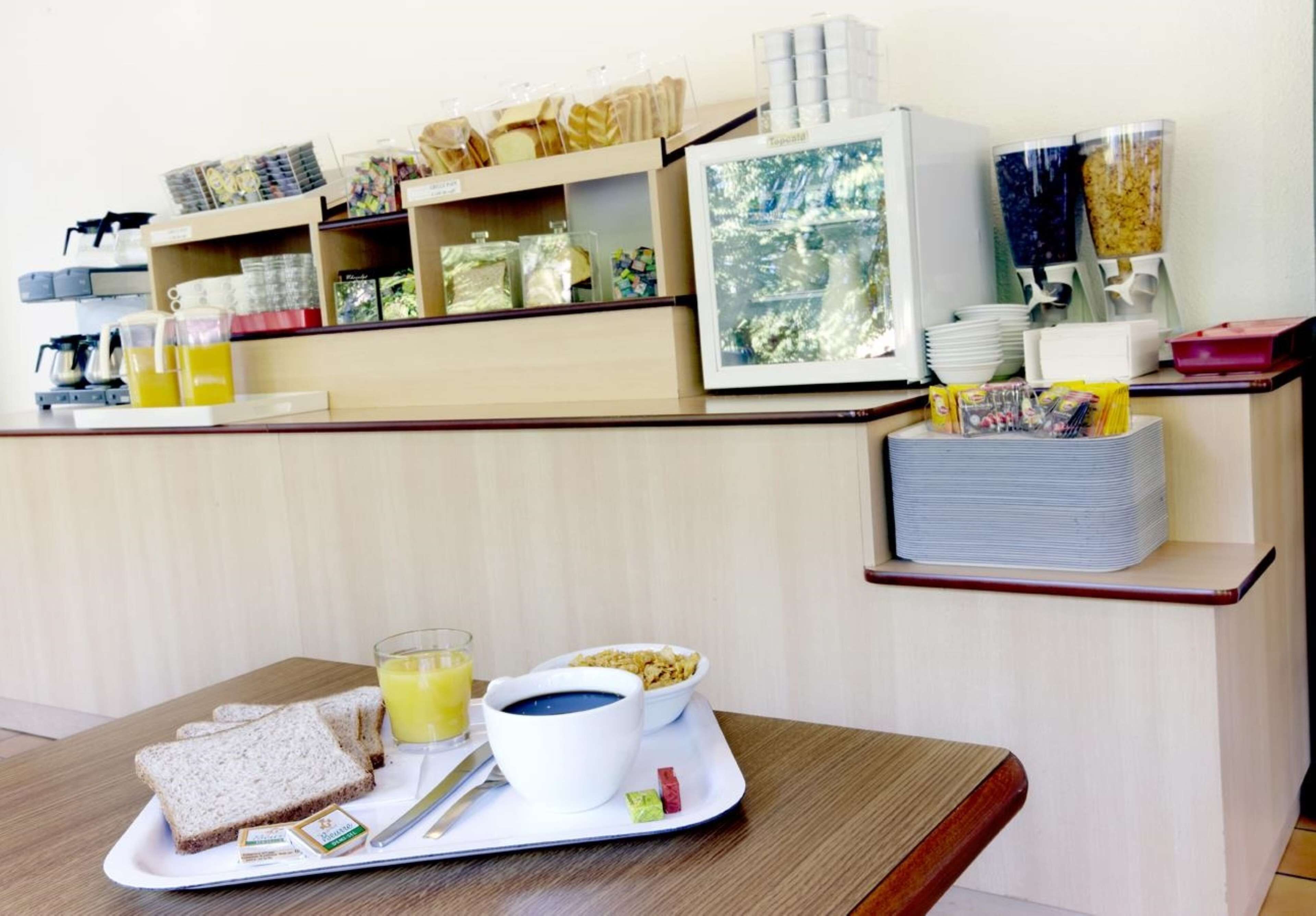 Uma bandeja de café da manhã com torradas, suco de laranja e cereal sobre uma mesa em um quarto de hotel.