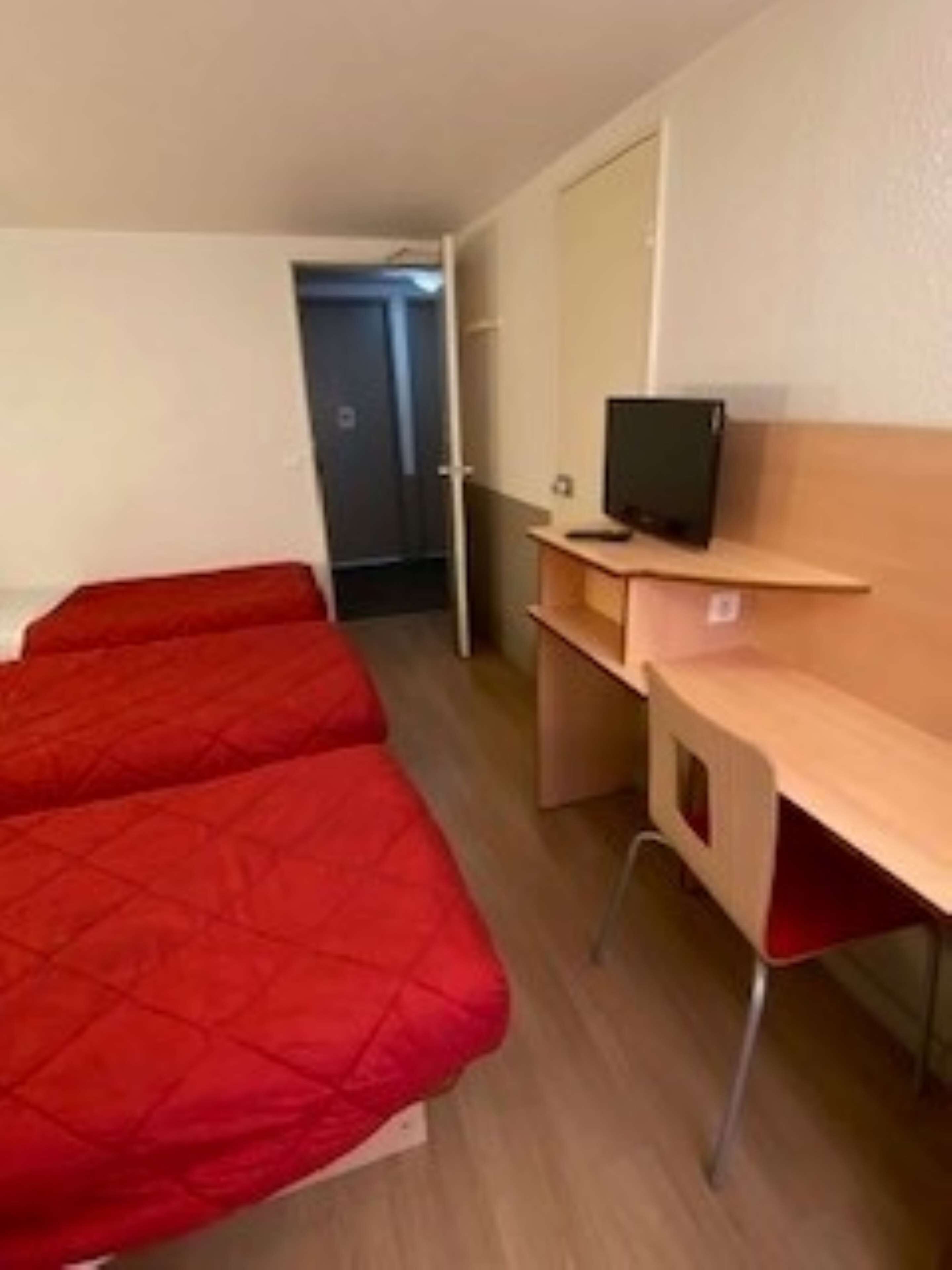 Ein Zimmer mit zwei Einzelbetten, einem Schreibtisch mit Computer und einem Kleiderschrank.