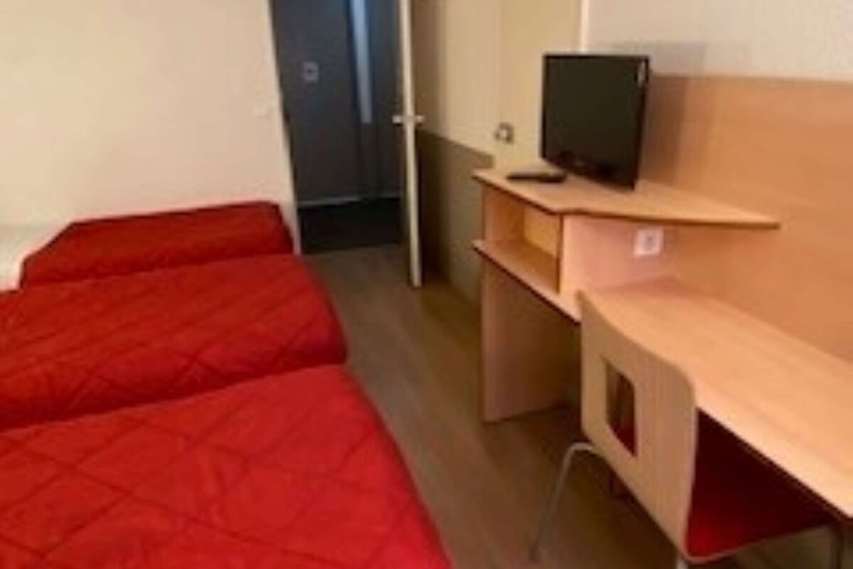 A room with two single beds, a desk with a computer, and a wardrobe.