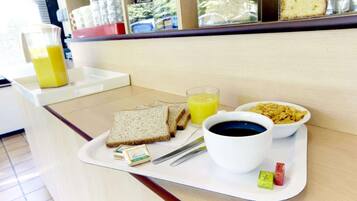 Bandeja de desayuno con tostadas, jugo, café y un tazón de cereal.