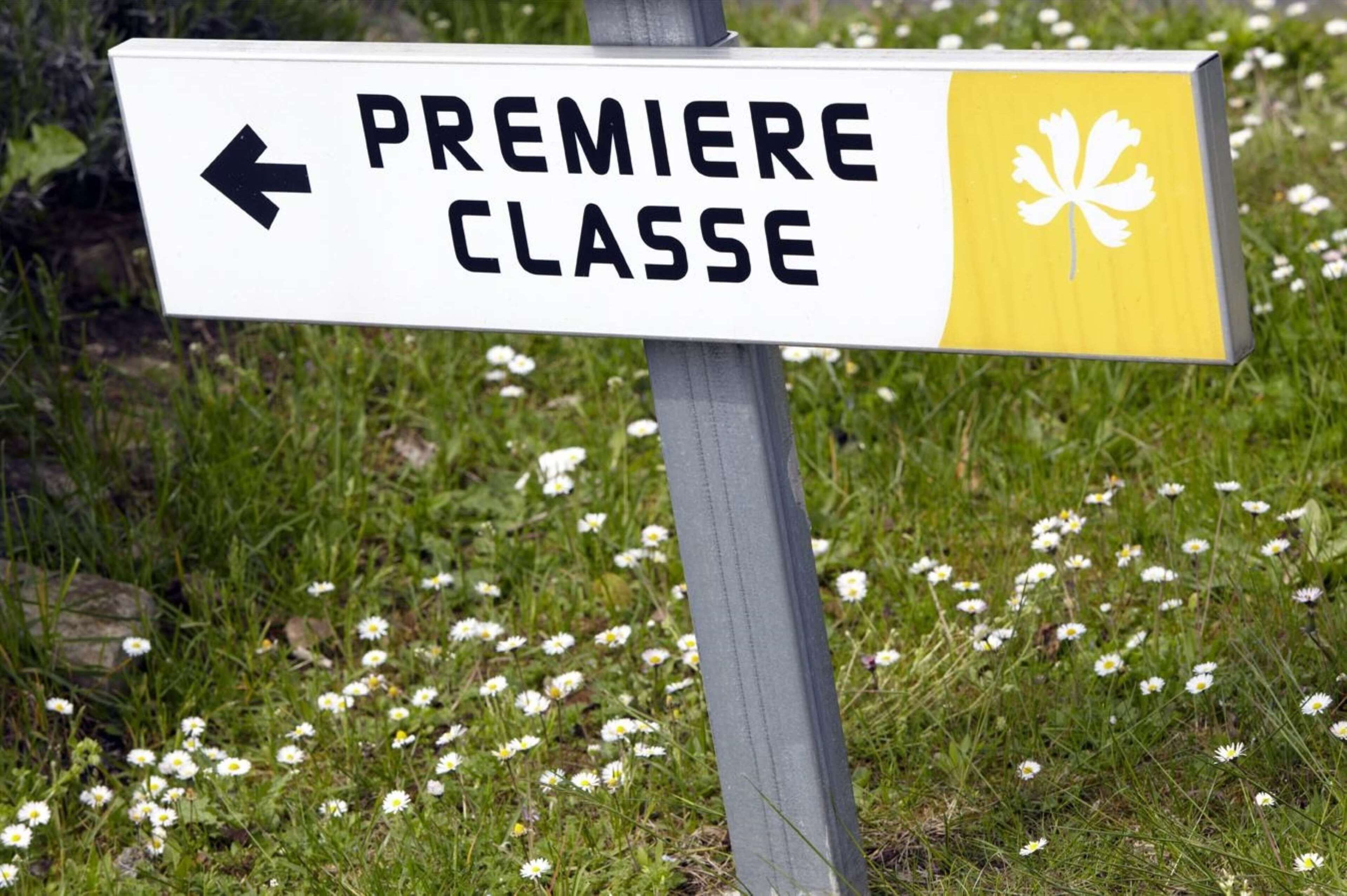 Un segnale direzionale con il testo 'PREMIERE CLASSE' e un simbolo a forma di foglia d'acero.