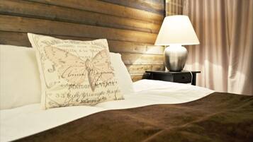 A neatly made bed with a white pillow and a decorative pillow with text. There is a bedside table with a lamp and a wooden headboard.